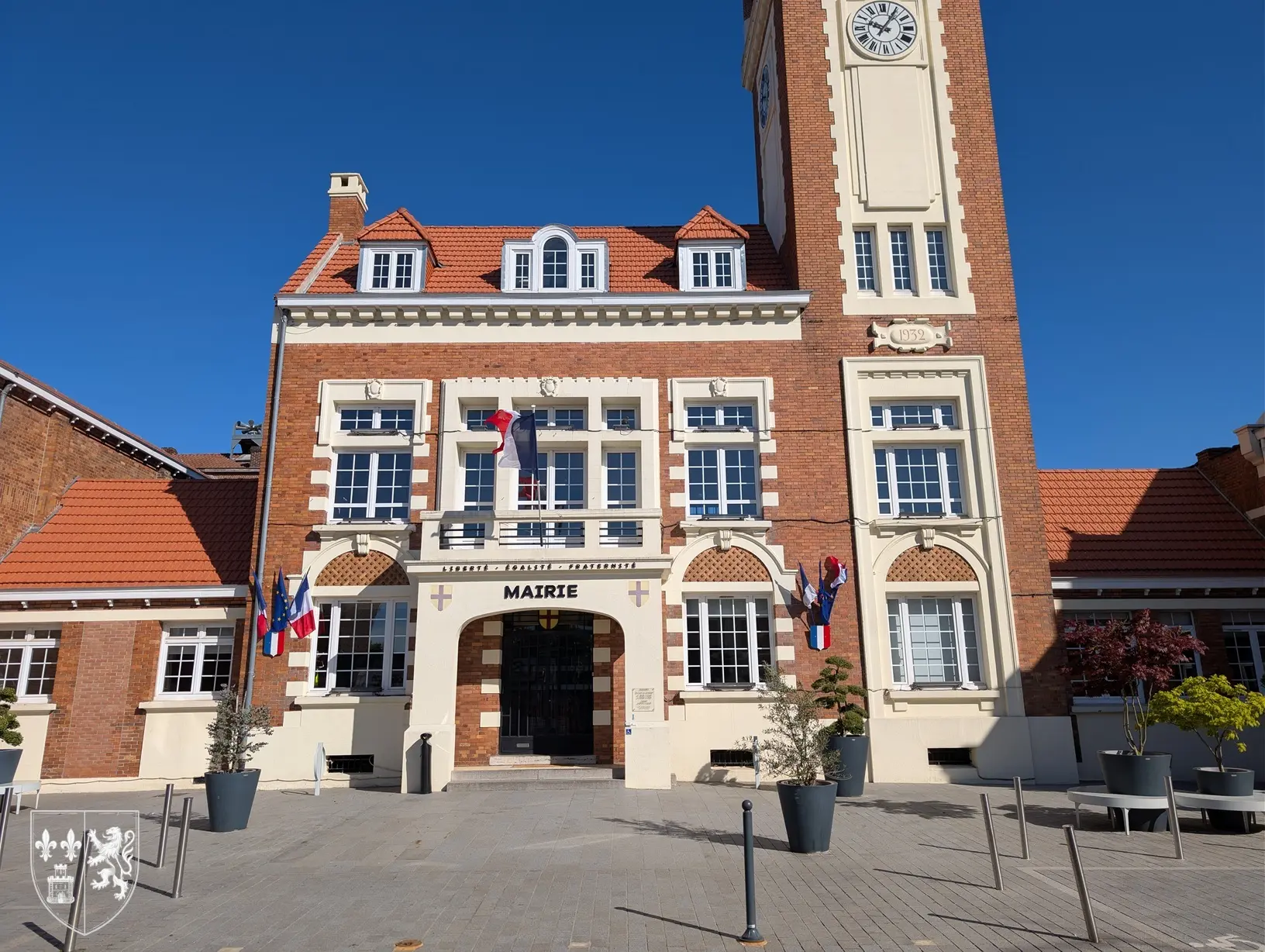 Façade de la mairie de Lesquin avec son beffroi et son horloge sous un ciel bleu