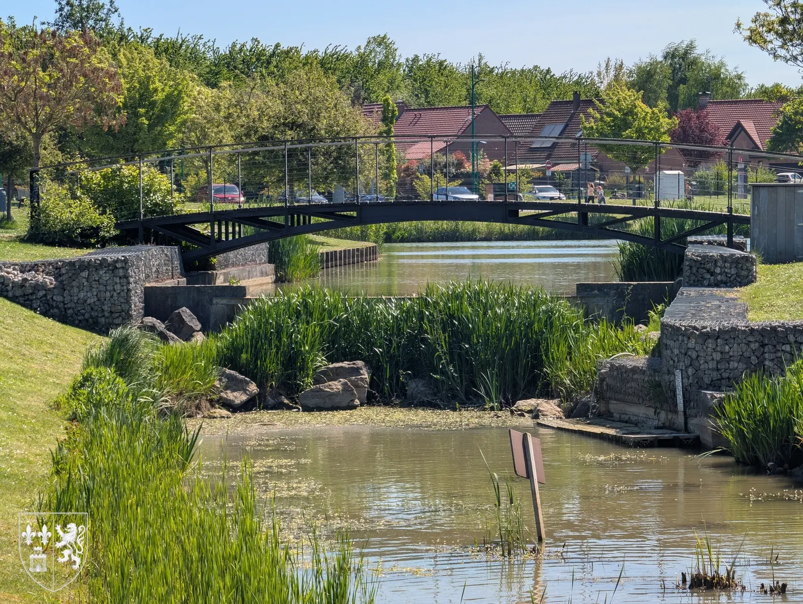 Passerelle au-dessus du plan d’eau de Merchin à Lesquin entouré de verdure